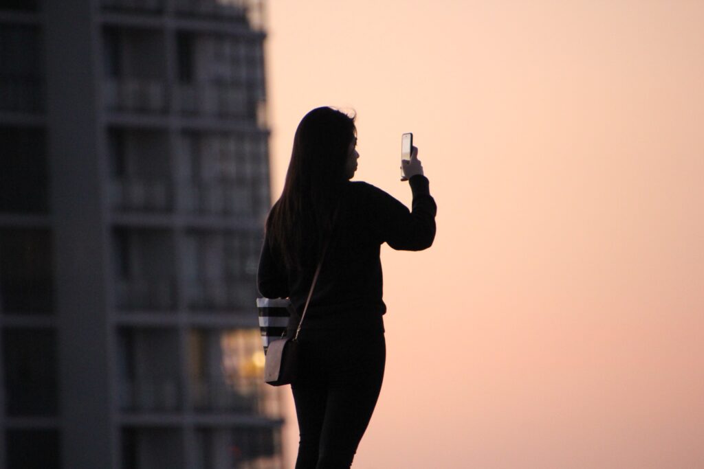 woman in black top using smartphone