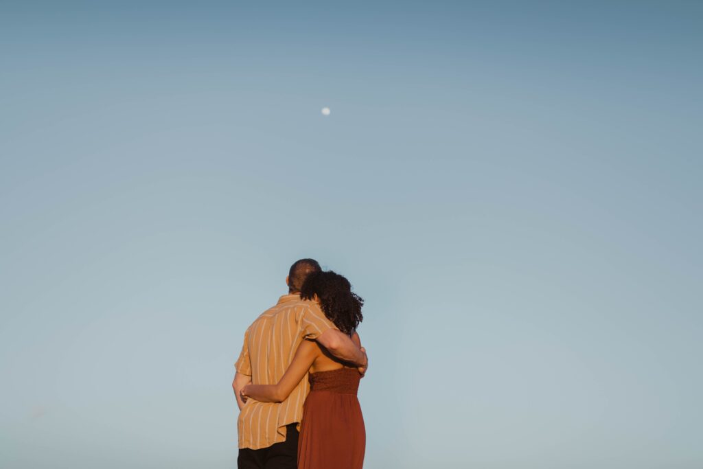 man and woman kissing under blue sky during daytime