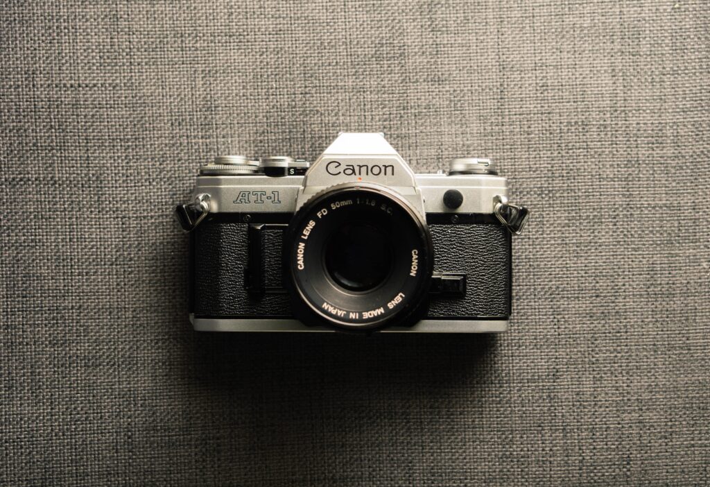 black and gray Canon camera on gray textile